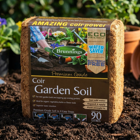 A Brunnings 90L Mega Coir Garden Soil Mulch Block rests on garden soil, providing excellent water retention and is ready to use as a premium coir garden soil mulch block.