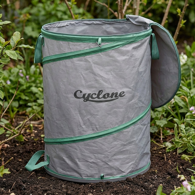 A Cyclone 175L Premium Pop-Up Garden Bag in gray and green sits on garden soil, ideal as a collapsible leaf collection bag for all your yard cleanup needs.