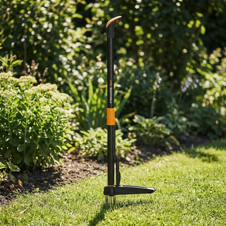 The Trojan Carbon Steel Pruning Saw stands upright on a grassy lawn beside green plants and shrubs, ready to assist with garden maintenance and pruning thicker branches.