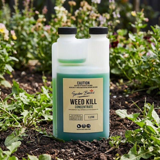 Garden Basics 1L Weed Kill Concentrate sits on soil among green plants in a garden, providing effective weed control.