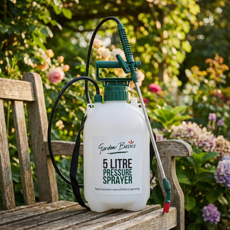The Garden Basics 5L Garden Pressure Sprayer Kit rests on a wooden bench in a garden, with blooming flowers visible in the background.
