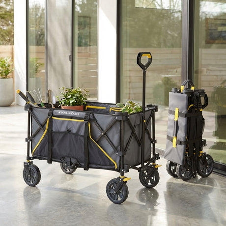 Gorilla Carts Folding Sports Wagon - 180 Litres, in gray and yellow, holds plants and tools beside a folded cart on a patio.