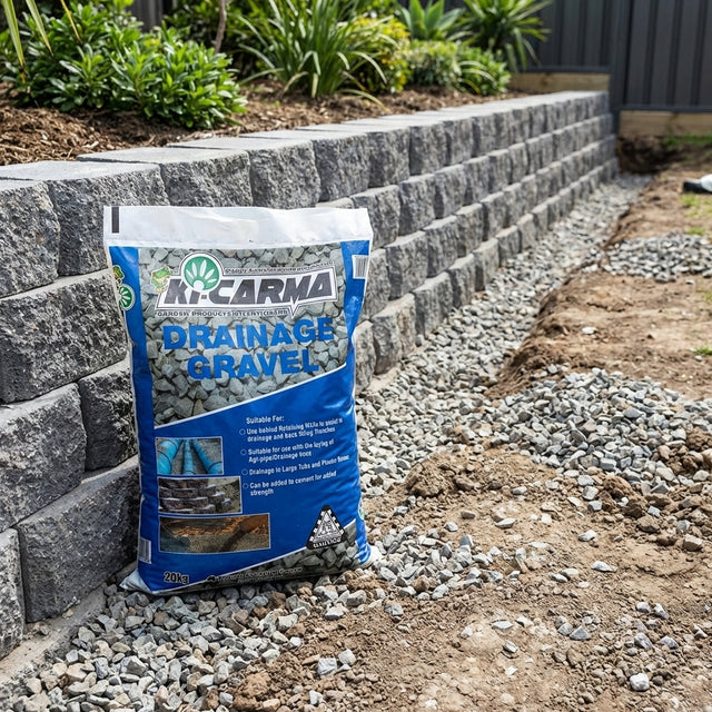 A 20kg bag of Ki Carma 10 to 20mm Drainage Gravel sits by a stone retaining wall, with loose gravel spread along the base for landscaping.
