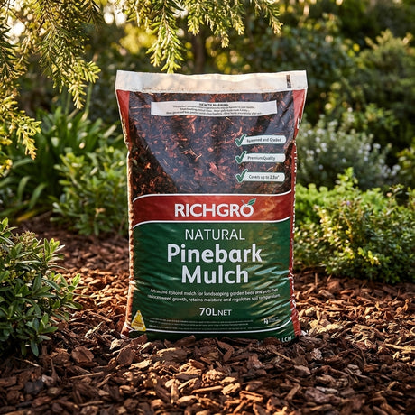 A bag of Richgro 70L Pine Bark Mulch covers garden beds, surrounded by plants and greenery, helping retain moisture for a healthier garden.