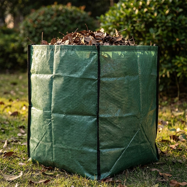 The Saxon 730L Jumbo Garden Bag, filled with dry leaves, sits on grass in a sunny outdoor area.