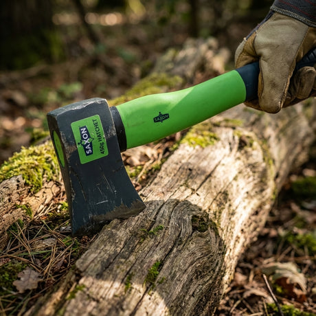 A gloved hand uses the Cyclone 3 Prong Lawn Aerator with a green handle to aerate a mossy log outdoors, demonstrating the importance of preventing soil compaction.