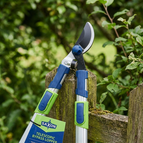Close-up of telescopic bypass loppers on a wooden fence with green foliage in the background—ideal for pairing with precision grass trimming tools like the Cyclone 330mm Straight Shears.