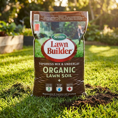 A bag of Scotts Lawn Builder 25L Organic Lawn Soil Topdress & Underlay, ideal for topdressing, rests on green grass in a sunlit garden.