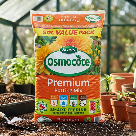 A 50L bag of Scotts Osmocote 50L Premium Potting Mix sits in a greenhouse among potted plants, providing premium potting mix with controlled release feeding for healthy plant growth.