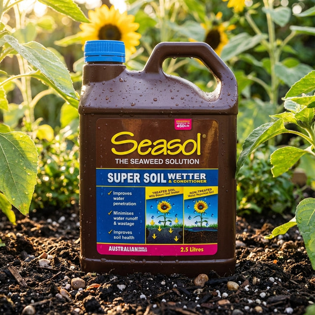A bottle of Seasol 2.5L Super Soil Wetter And Conditioner rests on garden soil, surrounded by lush green plants and sunflowers in the background.