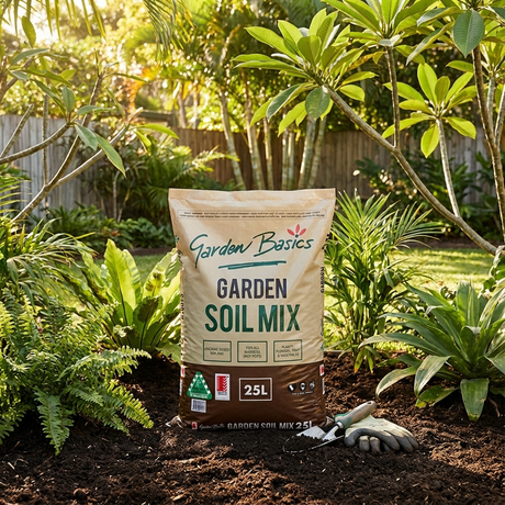 A bag of Garden Basics 25L Garden Soil Mix rests in a vibrant garden, accompanied by a trowel and gloves—ideal for enriching your soil and nourishing garden beds.